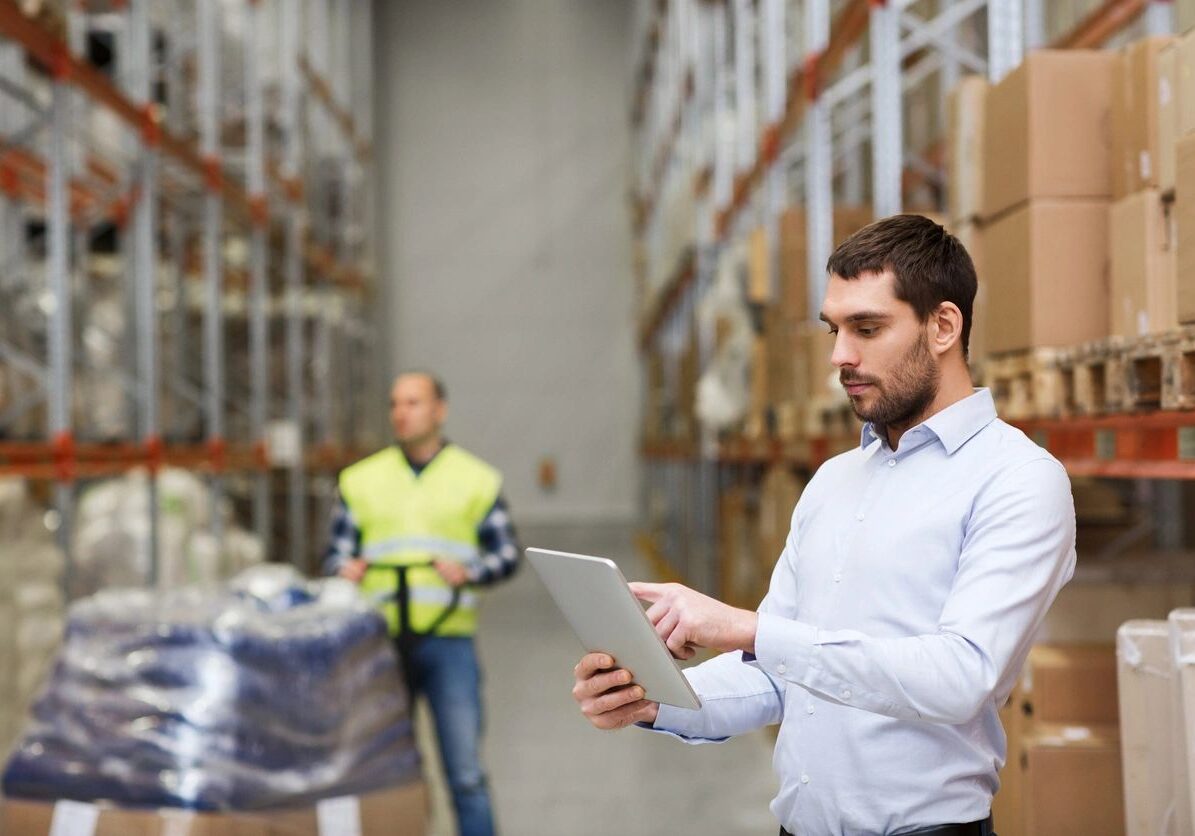 A man holding a tablet in a warehouse.